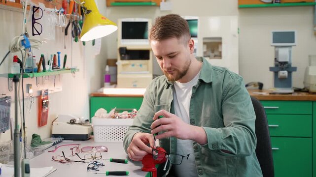 Optician repairing eyeglasses with a screwdriver in his workshop