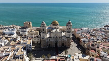Aerial view of Cadiz Cathedral and its iconic golden dome by the sea. Cinematic drone shot of the historic landmark and the Atlantic Ocean coastline in Andalusia, Spain © Pablohasday
