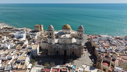 Aerial view of Cadiz Cathedral and its iconic golden dome by the sea. Cinematic drone shot of the historic landmark and the Atlantic Ocean coastline in Andalusia, Spain © Pablohasday