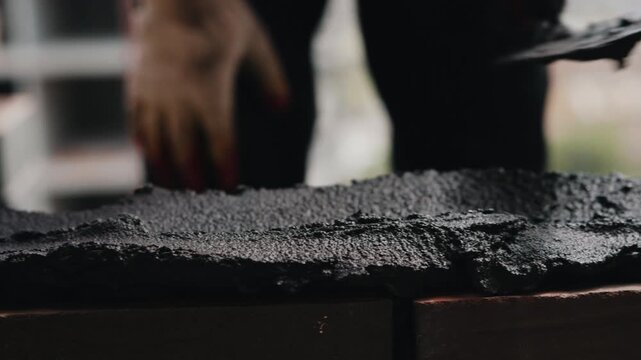 Applying cement mortar on brick wall during masonry work close up