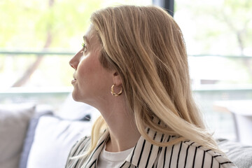 Thoughtful Blonde Woman Looking Out Window in Casual Striped Shirt Interior Portrait © luciano
