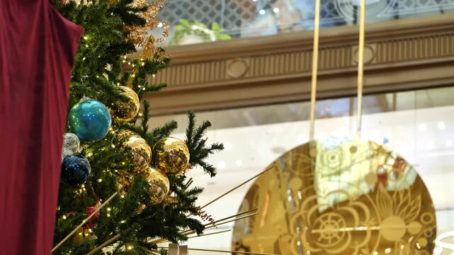 A decorated Christmas tree against the backdrop of a swinging clock pendulum.