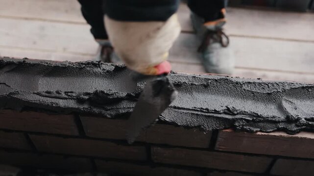 Applying mortar on brick wall during masonry construction close up