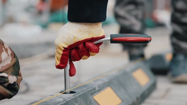 Worker tightening bolt on rubber parking wheel stop close up