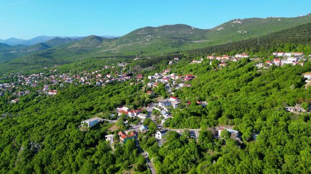 Aerial view of a vibrant Hreljin village nestled amidst the lush green hills of Croatia's Adriatic hinterland on a clear spring afternoon. Serene landscape.