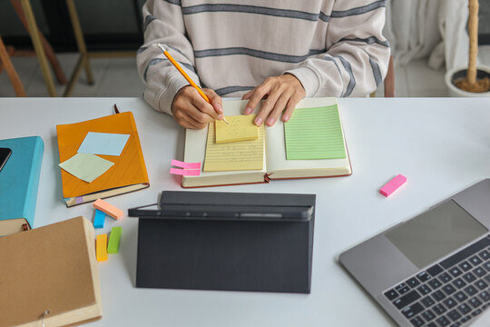 Young man taking notes while watching online course or webinar.