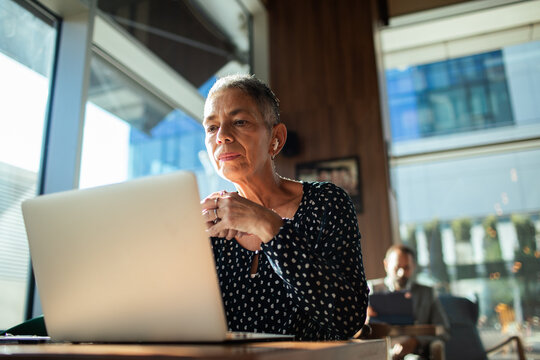 Senior woman working on laptop in modern cafe