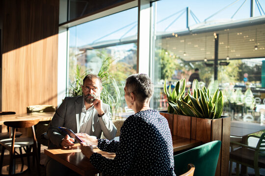 Business colleagues meeting with documents in a sunny cafe