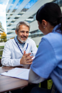 Senior doctor mentoring nurse during outdoor hospital meeting