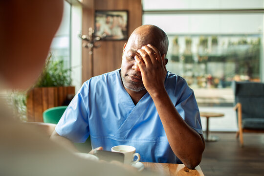 Stressed nurse rubbing forehead in cafe
