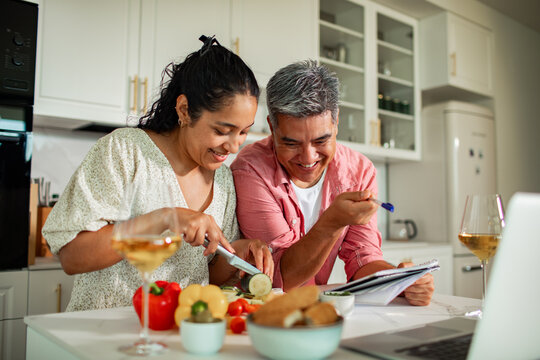 Smiling couple cooking dinner together in a modern home kitchen