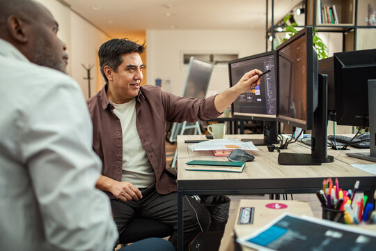 Designers collaborating at computer monitors in modern office