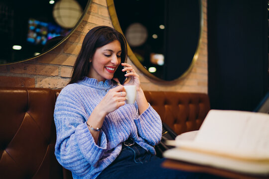 Smiling female model having mobile phone call and drinking espresso in cafe, remote worker multitasking, 5G connection, digital communication, modern business lifestyle, authentic people