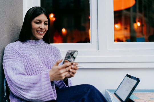 Thoughtful young woman looking away holding tablet and electronic pencil. Concept of dreaming, vision, career growth, digital planning. Female freelancer working in modern workspace environment.