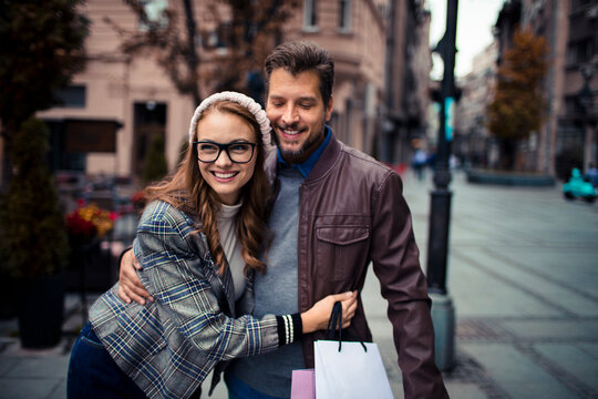 Smiling couple with shopping bags on city street