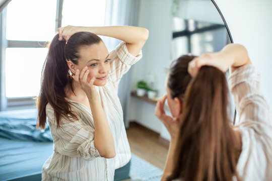 Young woman checking skin in mirror at home