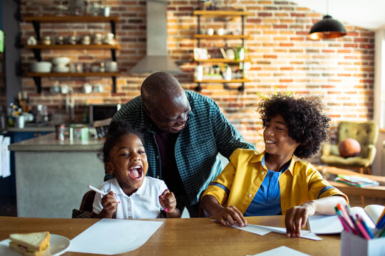 Parent helping children with homework at kitchen table