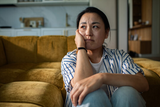 Worried woman sitting on couch at home