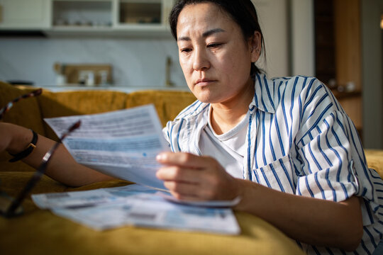 Concerned woman reviewing bills on sofa at home