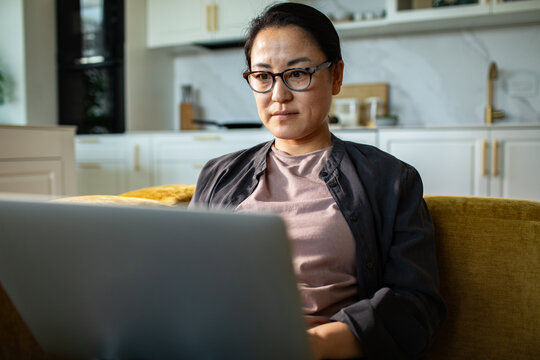Woman working on a laptop on sofa in home kitchen