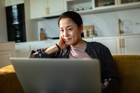 Smiling woman working on laptop in modern kitchen