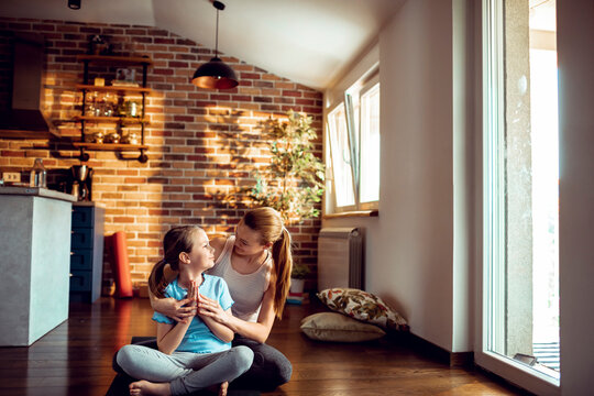 Mother and daughter practicing yoga in sunny living room