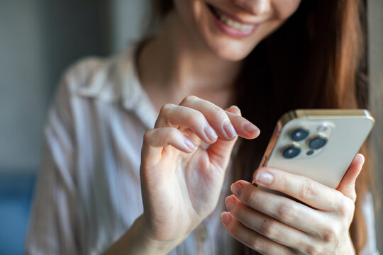 Close-up of woman's hands using smartphone at home