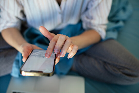 Person texting on smartphone at home in bed