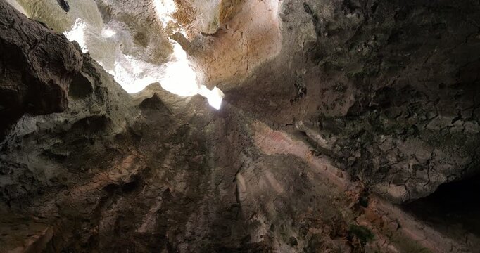 Incredible rock formations inside cave at Shilin Stone Forest in Kunming, narrow opening allows sunlight to filter through, illuminating rugged stone textures. Camera looks straight upward and spin