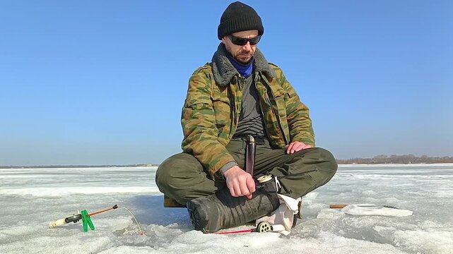 A man fishes on the ice of a frozen lake