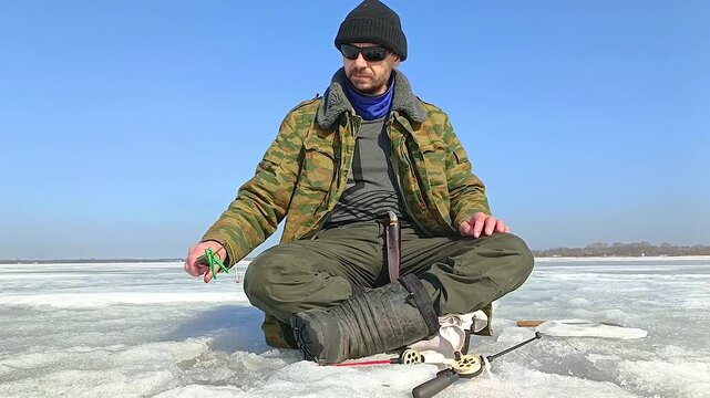 A man fishes on the ice of a frozen lake
