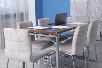 Fototapeta premium Stylish chairs and wooden table in office