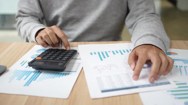 Financial planning and budgeting are essential for individuals and businesses. This shows a person using a calculator and analyzing various business reports and charts on a desk.