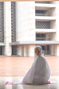 Muslim Woman in White Mukena Praying on Rug at Istiqlal Mosque Jakarta