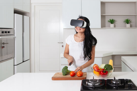 Smiling Woman Wearing VR Headset While Preparing Food in Modern Kitchen