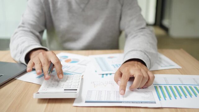 Financial planning and budgeting are essential for individuals and businesses. This shows a person using a calculator and analyzing various business reports and charts on a desk.
