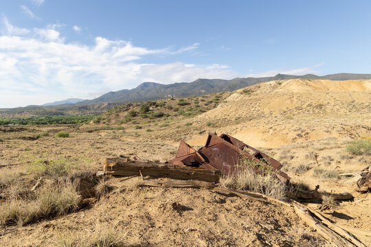 Desert Hills Landscape with Rusty Metal Mining Relics and Dramatic Cloudy Sky