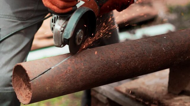 Experienced technician performs precise metal cutting with industrial grinder and protective gloves. Scene reflects craftsmanship, technical skills and reliable production work in modern industry.