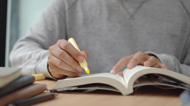 Student highlighting textbook for education and exam preparation concept.