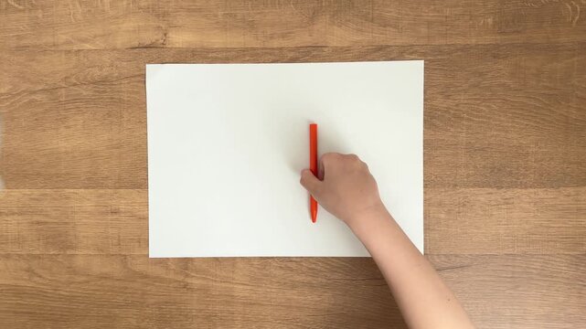 Child's Hand Placing an Orange Pen on A4 Paper, 4K Slow Motion