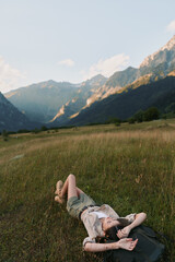 Fototapeta premium Woman lifestyle outdoor relaxation nature mountains meadow sunlight carefree scenery, casual clothing, serene moment, bright colors in a natural setting
