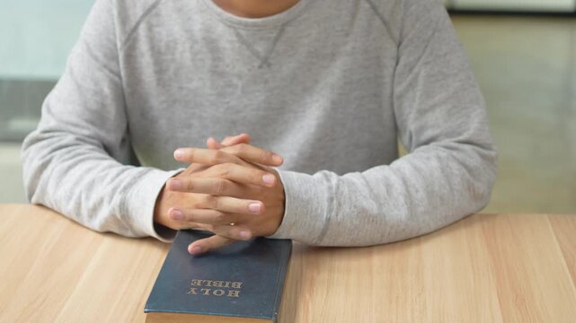 A person reading the Bible and praying in a devotional moment of faith and reflection.