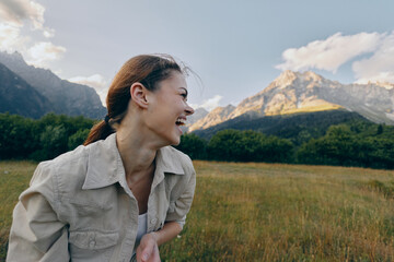 Fototapeta premium woman outdoors smiling in a sunlit field with mountains in the background, casual jacket, relaxed lifestyle moment, natural colors, breezy atmosphere