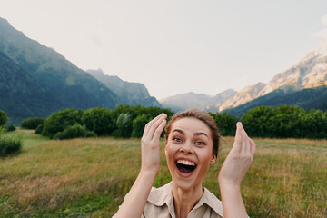 Fototapeta premium Joyful woman outdoors in a mountain valley with a wide smile and surprised expression embracing natural landscape candid lifestyle moment, clear sky and fresh air peaceful mood.