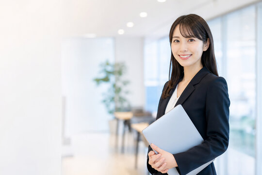 オフィスでノートPCを持つスーツの日本人女性 Generative AI