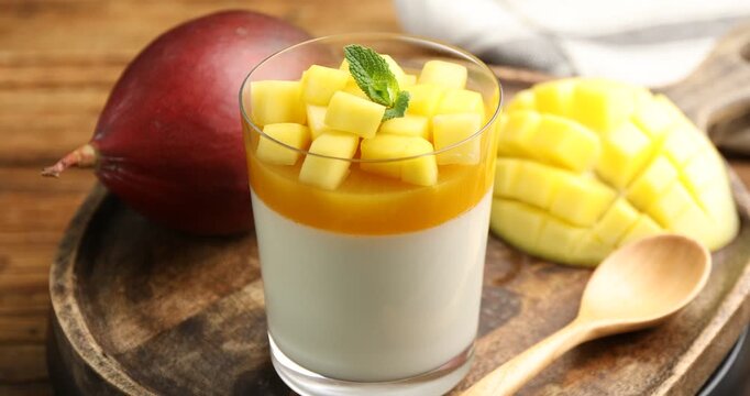 Delicious mango panna cotta with mint and fresh fruits on wooden table, closeup