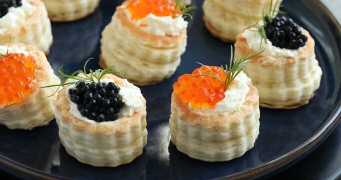 Tasty puff pastries with cream cheese, caviar and dill on plate, closeup