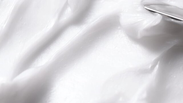 Close-up of white cosmetic cream texture being smoothed with a spatula