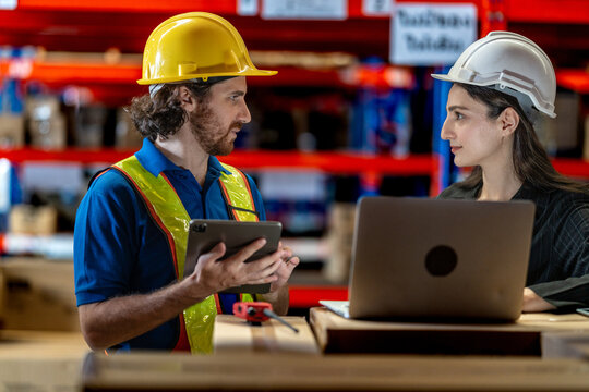 Collaborative logistics team reviewing stock availability in a large warehouse. Industrial specialist pointing at high shelves with a manager for inventory audit and strategic planning.