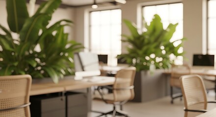 Fototapeta premium Blurred modern office interior with green plants, desks, and chairs, featuring soft focus and warm natural light from windows